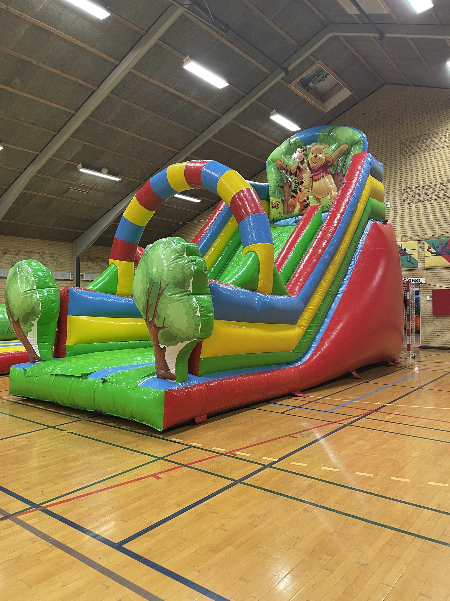 Oppustelig sklie i gymnastiksal med farverige buer.